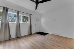 Wood-finish flooring, two large windows, a ceiling fan, and a front entry door with decorative glass - 