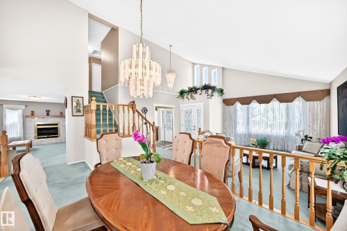 Elegant dining room showcasing a wood oval table, upholstered chairs, and a striking multi-tiered crystal chandelier - 4327 49 Street Nw, Edmonton, AB 