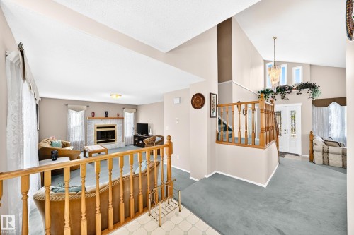 Open-concept upper level featuring vaulted ceilings, wood railings, and natural light from multiple windows - 4327 49 Street Nw, Edmonton, AB 