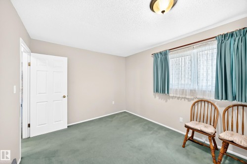Carpeted room with neutral wall tones, a paneled door, and a multi-paned window - 4327 49 Street Nw, Edmonton, AB 