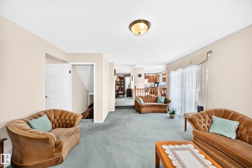 Spacious living area with multiple seating zones, neutral wall finishes, and abundant natural light from dual window sets - 4327 49 Street Nw, Edmonton, AB 