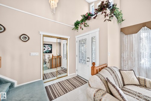 Bright primary bedroom featuring large windows with natural light, mirrored closet doors, striped area rug, neutral wall finishes, and access to an ensuite bathroom visible through the open doorway - 4327 49 Street Nw, Edmonton, AB 