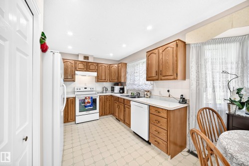 Spacious kitchen featuring wood-finish cabinetry, white appliances, ceramic tile flooring, and ample counter space - 4327 49 Street Nw, Edmonton, AB 