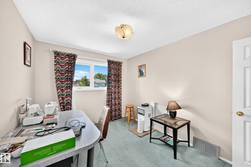 Versatile home office featuring abundant natural light from a multi-pane window, neutral wall finishes, wood-finish flooring, and ample space for dual workstations - 4327 49 Street Nw, Edmonton, AB 