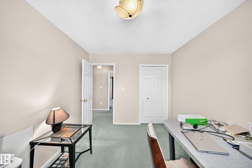 Versatile office or bedroom space featuring neutral wall finishes, ceiling-mounted lighting fixture, and direct access to an ensuite bathroom - 4327 49 Street Nw, Edmonton, AB 