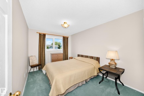 Serene bedroom retreat featuring soft neutral walls, wood-finish furnishings, and sage green flooring - 4327 49 Street Nw, Edmonton, AB 
