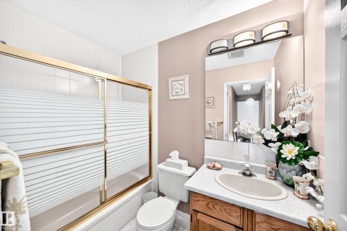 Spa-inspired bathroom featuring a double-sink vanity with wood-finish cabinetry, dual mirrors with integrated lighting, and a ceramic vessel sink - 4327 49 Street Nw, Edmonton, AB 