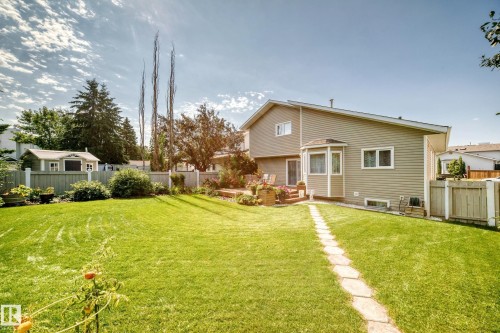 Expansive yard with green lawn, stone pathway, wood deck, and a storage shed - 4327 49 Street Nw, Edmonton, AB 
