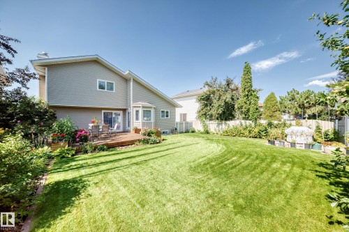 Expansive backyard featuring a manicured lawn, a wood-finish deck, and surrounding mature landscaping - 4327 49 Street Nw, Edmonton, AB 