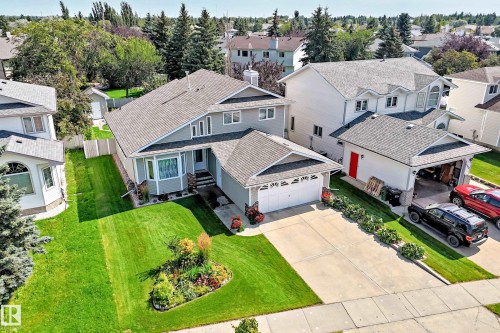 Two-story residence featuring a front-facing attached garage, concrete driveway, and a landscaped front yard with a garden bed - 4327 49 Street Nw, Edmonton, AB 