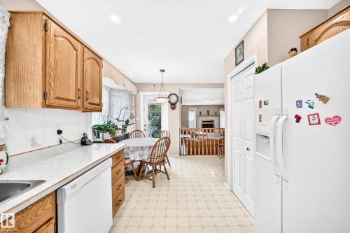 Galley-style kitchen featuring wood cabinetry, white countertops, white appliances, and ceramic tile flooring - 4327 49 Street Nw, Edmonton, AB 