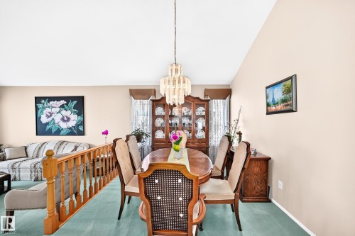 Elegant dining room featuring a wood-finish table with coordinating chairs, crystal chandelier, and abundant natural light from vaulted ceilings - 4327 49 Street Nw, Edmonton, AB 