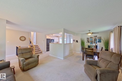 Open-concept living area featuring neutral wood-finish flooring, a half-wall kitchen partition with pass-through counter, recessed ceiling lighting, and multiple windows with natural light - 14 Brunswick Crescent, St. Albert, AB 