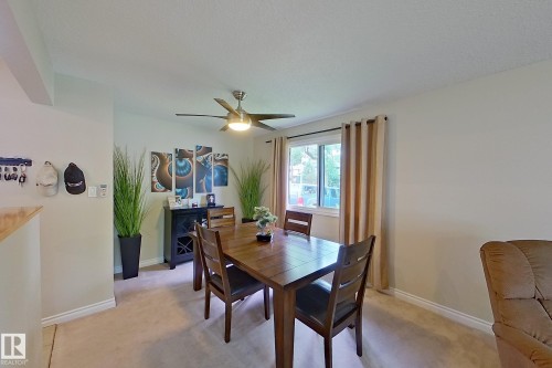Bright dining area with wood-finish flooring, ceiling fan with integrated lighting, and sliding glass doors providing natural light - 14 Brunswick Crescent, St. Albert, AB 