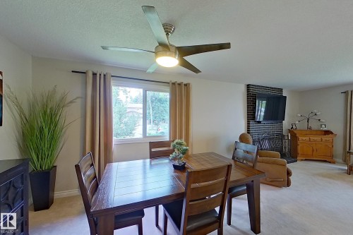 Bright dining room with wood-finish table and chairs, ceiling fan with integrated lighting, and large windows with natural light - 14 Brunswick Crescent, St. Albert, AB 
