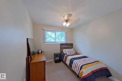 Bright secondary bedroom with carpet flooring, wood-finish dresser, and bedside nightstand - 14 Brunswick Crescent, St. Albert, AB 