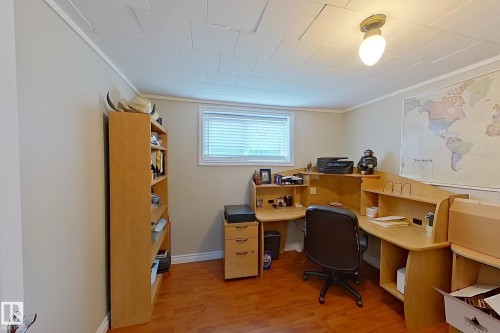 Dedicated home office featuring wood-finish cabinetry with ample built-in storage, hardwood flooring, a large operable window with natural light, and recessed ceiling lighting - 14 Brunswick Crescent, St. Albert, AB 