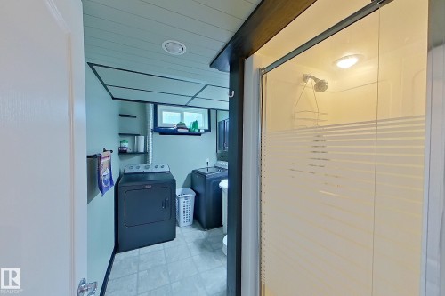 Modern bathroom suite featuring a frameless glass shower enclosure with horizontal accent striping, tile flooring, recessed ceiling lighting, and dual vanity setup with ample storage - 14 Brunswick Crescent, St. Albert, AB 