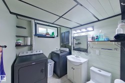 Dedicated laundry room featuring full-size front-load washer and dryer, white cabinetry with ample storage, utility sink with chrome fixtures, and recessed lighting throughout - 