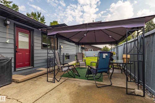 Outdoor entertaining space featuring a large retractable shade canopy, composite decking, metal fencing, and mature landscaping - 14 Brunswick Crescent, St. Albert, AB 