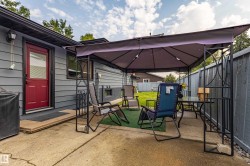 Outdoor entertaining space featuring a large retractable shade canopy, composite decking, metal fencing, and mature landscaping - 