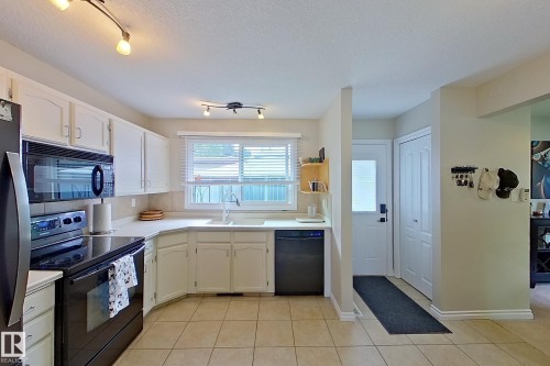 Kitchen featuring white cabinetry, black appliances, track lighting, and tile flooring - 14 Brunswick Crescent, St. Albert, AB 