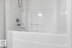 Integrated white bathtub and shower unit with chrome fixtures - 