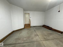 Garage with concrete flooring, white painted walls, and a single paneled door - 