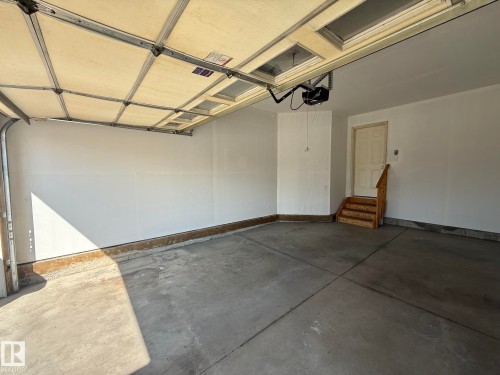 Spacious garage featuring an overhead door with natural light, concrete flooring, and finished drywall walls - 1807 Westerra Loop, Stony Plain, AB 
