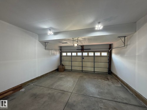 Attached garage with concrete flooring, white painted walls, and a paneled garage door with windows - 1807 Westerra Loop, Stony Plain, AB 