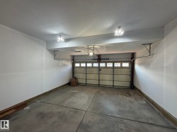 Attached garage with concrete flooring, white painted walls, and a paneled garage door with windows - 