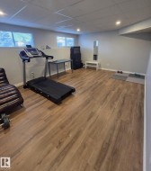 Expansive room with wood-finish flooring, recessed lighting, and two windows with blinds - 