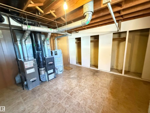 Finished basement with polished concrete flooring, exposed beam ceiling with integrated ductwork, and multiple finished room spaces featuring white-trimmed doorways - 7007 91 Avenue Nw, Edmonton, AB 