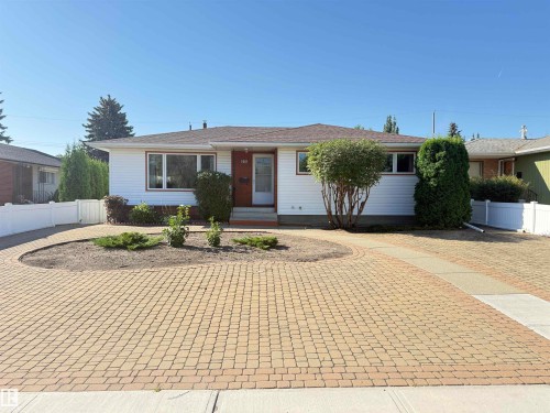 White siding exterior with a brown shingle roof, complemented by a red front door and white trim windows - 7007 91 Avenue Nw, Edmonton, AB 