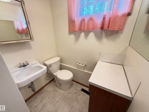 Functional half bath featuring a pedestal sink with chrome fixtures, a standard toilet, ceramic tile flooring, and neutral wall finishes - 7007 91 Avenue Nw, Edmonton, AB 