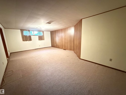 Spacious basement recreation room featuring carpeted flooring, recessed ceiling lighting, and multiple windows with wood-finish curtain treatments - 7007 91 Avenue Nw, Edmonton, AB 