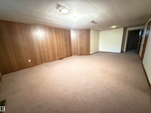 Spacious open room featuring neutral carpet flooring, wood-finish wall paneling, and recessed ceiling lighting - 7007 91 Avenue Nw, Edmonton, AB 