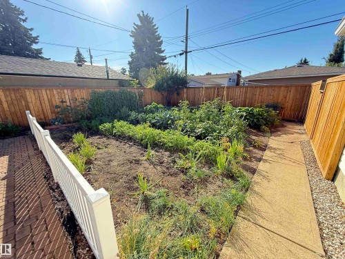 Fenced backyard with established garden beds, gravel pathways, and mature landscaping - 7007 91 Avenue Nw, Edmonton, AB 