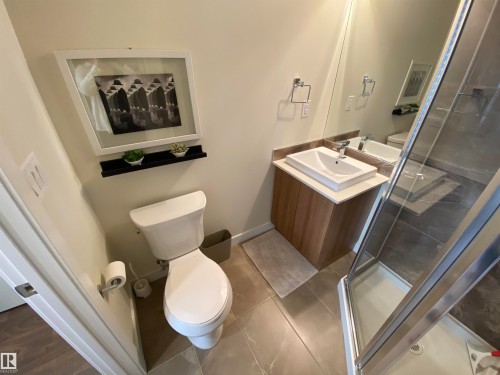 Modern bathroom with a wood-finish vanity, white countertop, vessel sink, and glass-enclosed shower - #308 9907 91 Av Nw, Edmonton, AB 