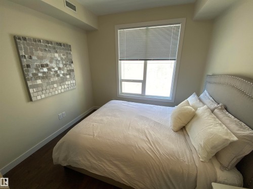 Well-lit room featuring wood-finish flooring, light-colored walls, and a window with blinds - #308 9907 91 Av Nw, Edmonton, AB 