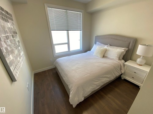 Light-filled room featuring wood-finish flooring, a window with blinds, and neutral wall tones - #308 9907 91 Av Nw, Edmonton, AB 