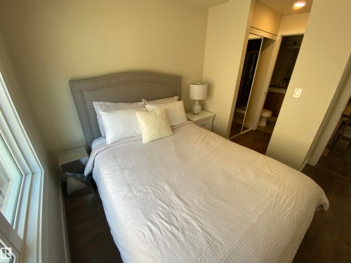 Window with white trim, wood-finish flooring, recessed lighting, mirrored closet doors, and an attached bathroom - #308 9907 91 Av Nw, Edmonton, AB 