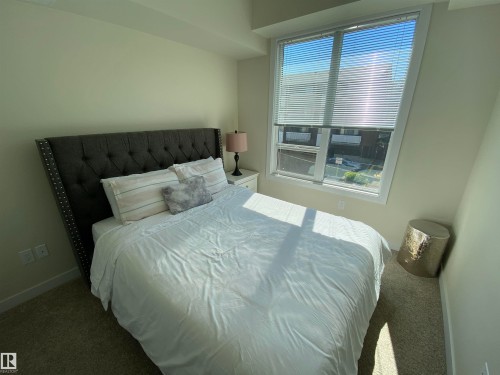 Light-colored carpeting, a large window with horizontal blinds, and neutral wall tones - #308 9907 91 Av Nw, Edmonton, AB 