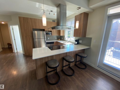 Kitchen featuring wood-finish cabinetry, stainless steel appliances, white countertops, and a built-in cooktop - #308 9907 91 Av Nw, Edmonton, AB 