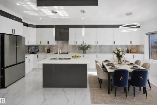 Contemporary kitchen featuring white high-gloss cabinetry, a dark gray island with a white countertop, and a tiled backsplash - 2027 13 Avenue Nw, Edmonton, AB 