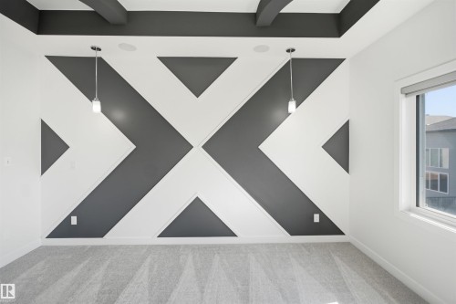 Accent wall with geometric design, suspended pendant lighting, textured carpet flooring, and a large window with roller shade - 2027 13 Avenue Nw, Edmonton, AB 