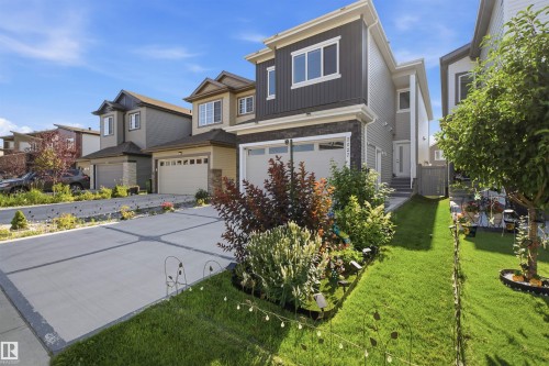 Modern exterior featuring dark siding, stone accents, an attached garage, and a concrete driveway - 2027 13 Avenue Nw, Edmonton, AB 