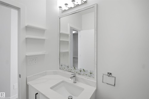 Vanity with white countertop, integrated sink, chrome faucet, and mirrored wall cabinet - 2027 13 Avenue Nw, Edmonton, AB 