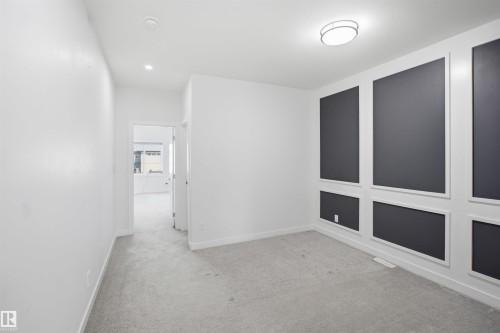 Accent wall with decorative molding, flush mount ceiling fixture, recessed lighting, white interior walls, and gray carpet - 2027 13 Avenue Nw, Edmonton, AB 