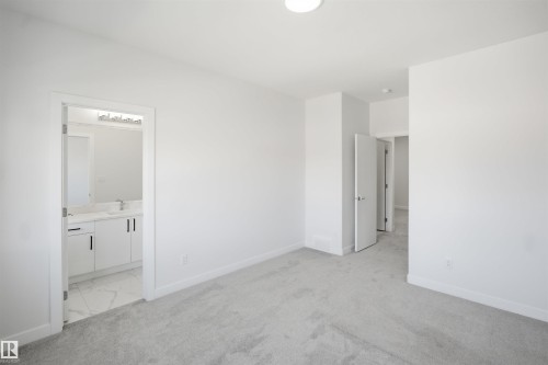 Plush grey carpeting, white interior doors, and a bathroom featuring a white vanity with dark hardware, a rectangular undermount sink, and patterned floor tile - 2027 13 Avenue Nw, Edmonton, AB 